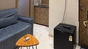 A room with a sofa, a small table, a black refrigerator, an air conditioner, and a mirror. - Vijaya's Homestay Indore (Indore)