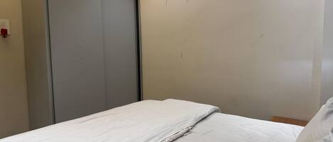 Ein Schlafzimmer mit einem Bett, einem Kleiderschrank und einer Steckdose.