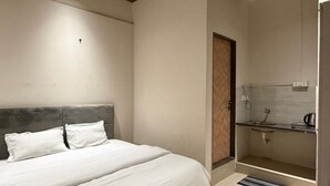 A bedroom with a bed, a ceiling fan, a wooden ceiling, a bathroom with a sink and mirror, and a tiled floor. - Vijaya's Homestay Indore (Indore)