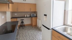 Una cocina compacta con microondas, refrigerador y encimera negra.