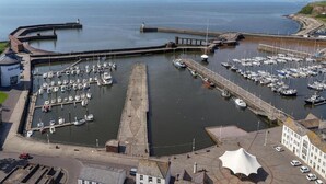 Un puerto deportivo con barcos amarrados, un faro y un edificio de fachada blanca.