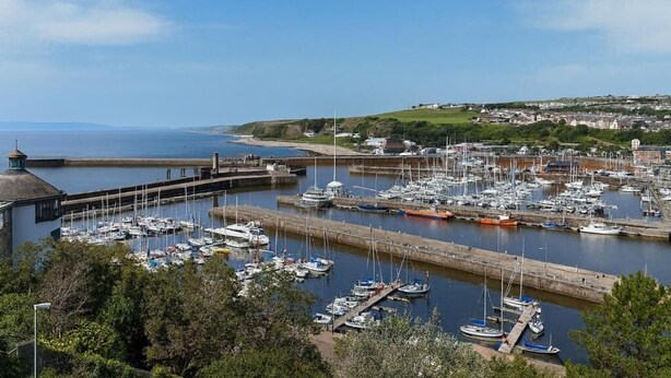 Un puerto deportivo con barcos amarrados, un muelle y vistas a la costa.