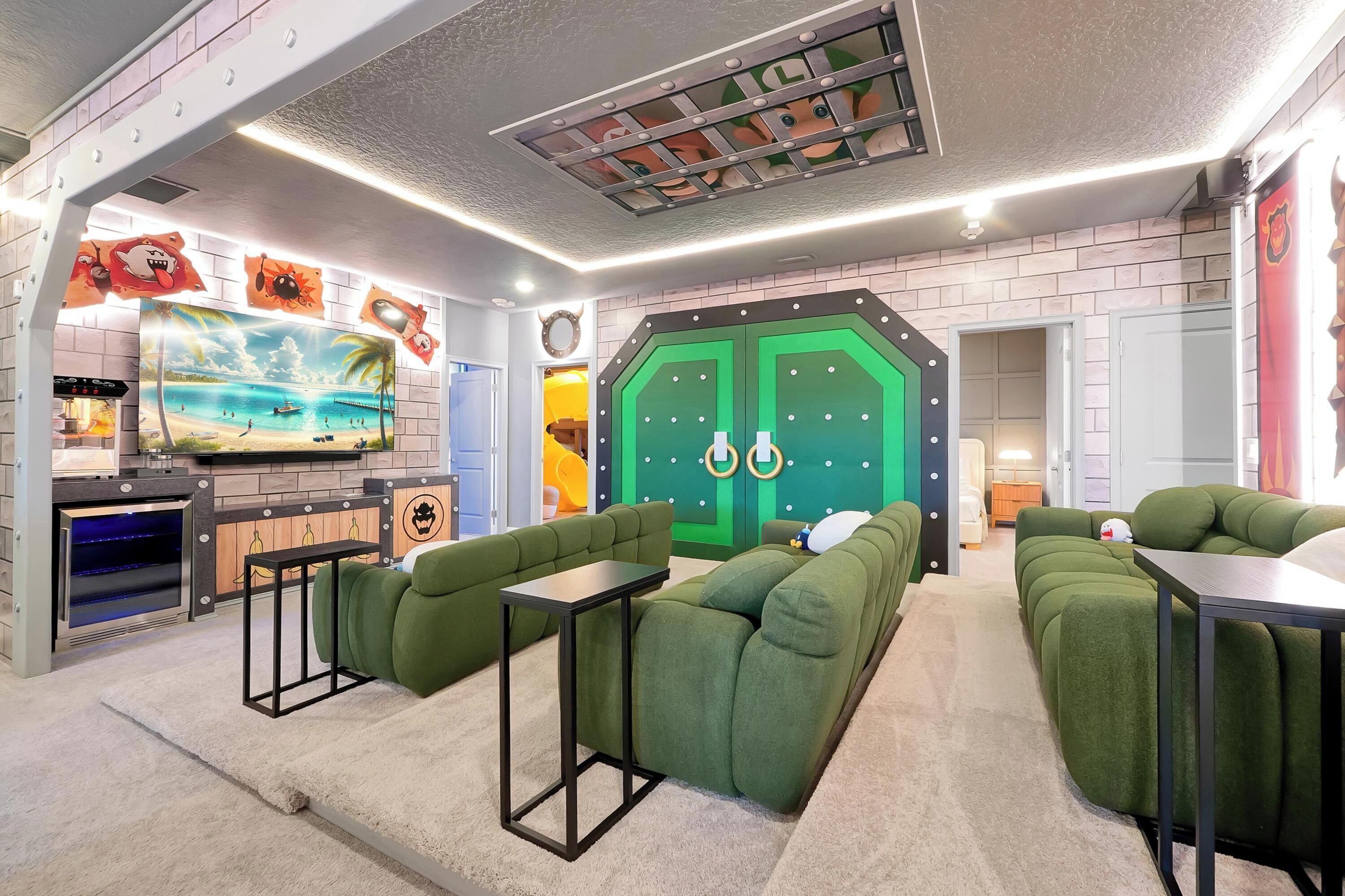 A room with green upholstered seating, a television, and a green door with circular decorations.