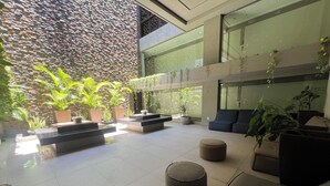 Un espai interior modern amb una paret de pedra, plantes en testos i zones d'estar.