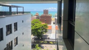 Vista des d'un balcó sobre un paisatge urbà amb edificis, un arbre i un cel serè.