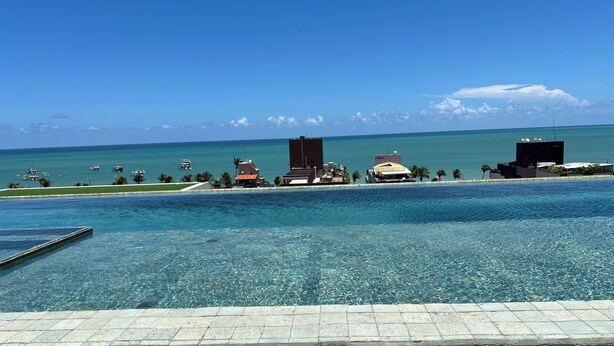 Una piscina nítida amb vista a l'oceà i edificis al fons.