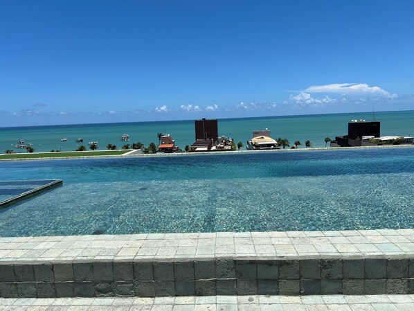 Ein klares Schwimmbecken mit Blick auf den Ozean und Gebäude im Hintergrund.