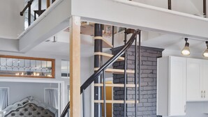 Ett modernt sovrum i loftstil med en stor säng, en trappa och ett köksutrymme.