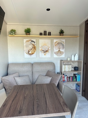 Un soggiorno moderno con un divano, un tavolino in legno e una libreria con libri e oggetti decorativi.