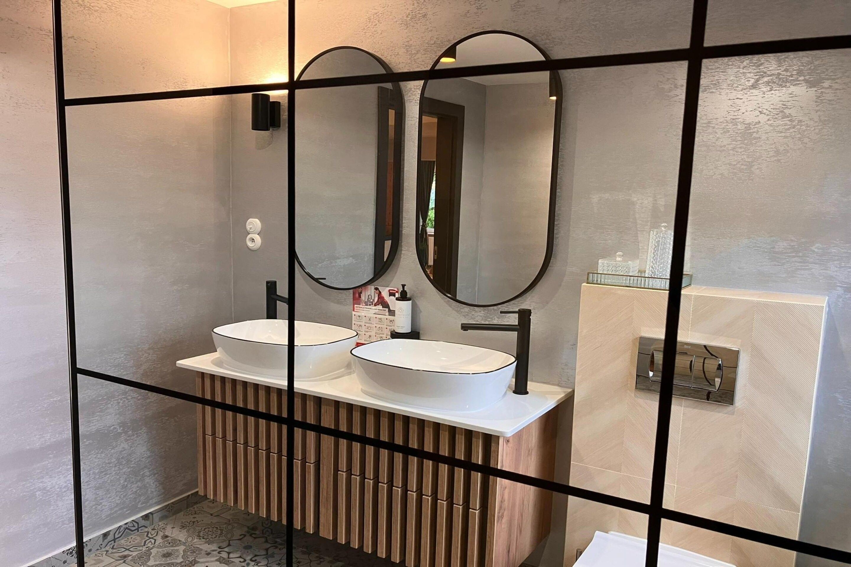 A modern bathroom with two sinks, a mirror, and a wooden vanity.