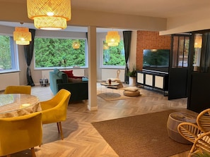 Una sala de estar moderna con un sofá, sillones, un televisor y una chimenea.