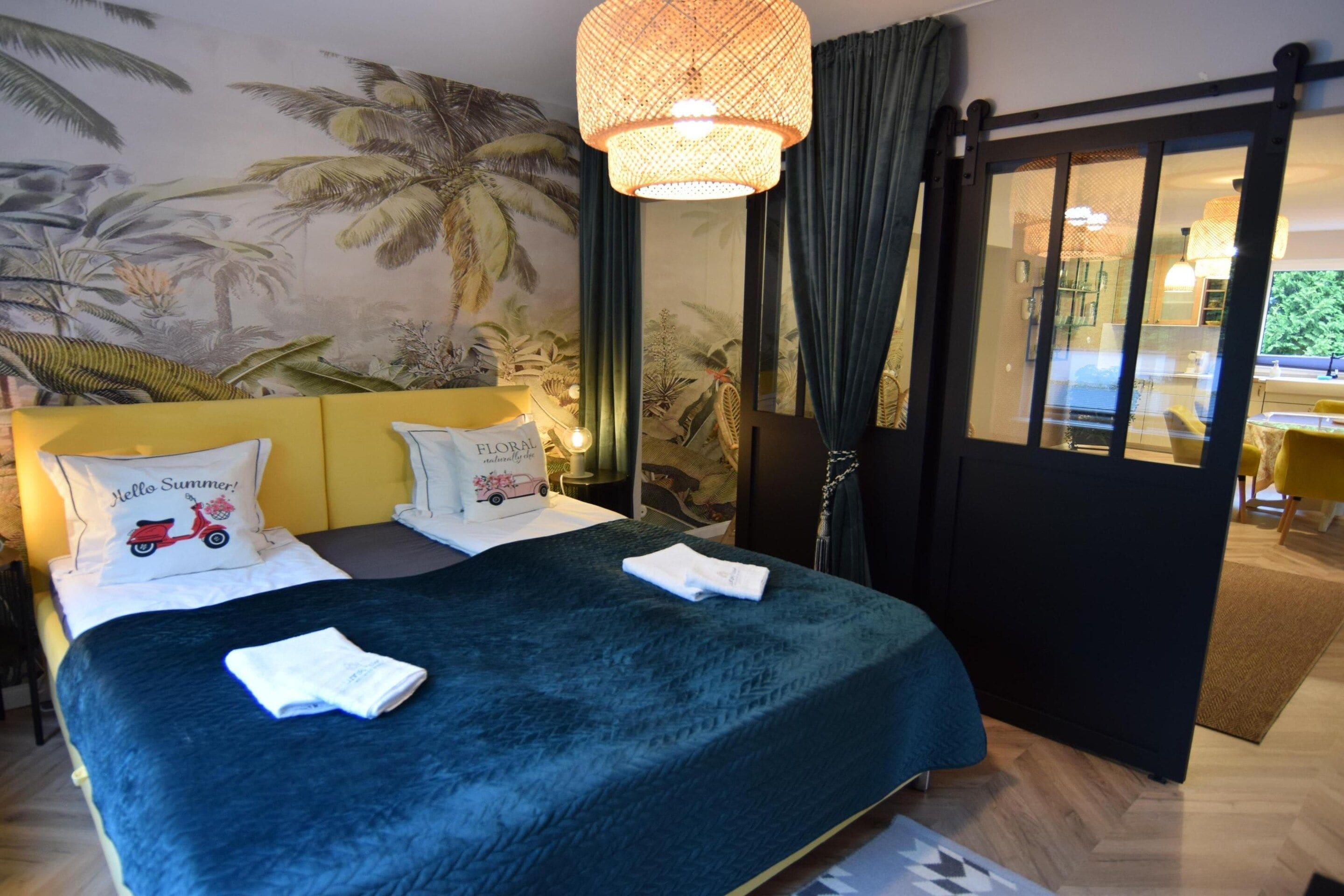 A hotel room with a bed, a large window, and a view of the outdoors.