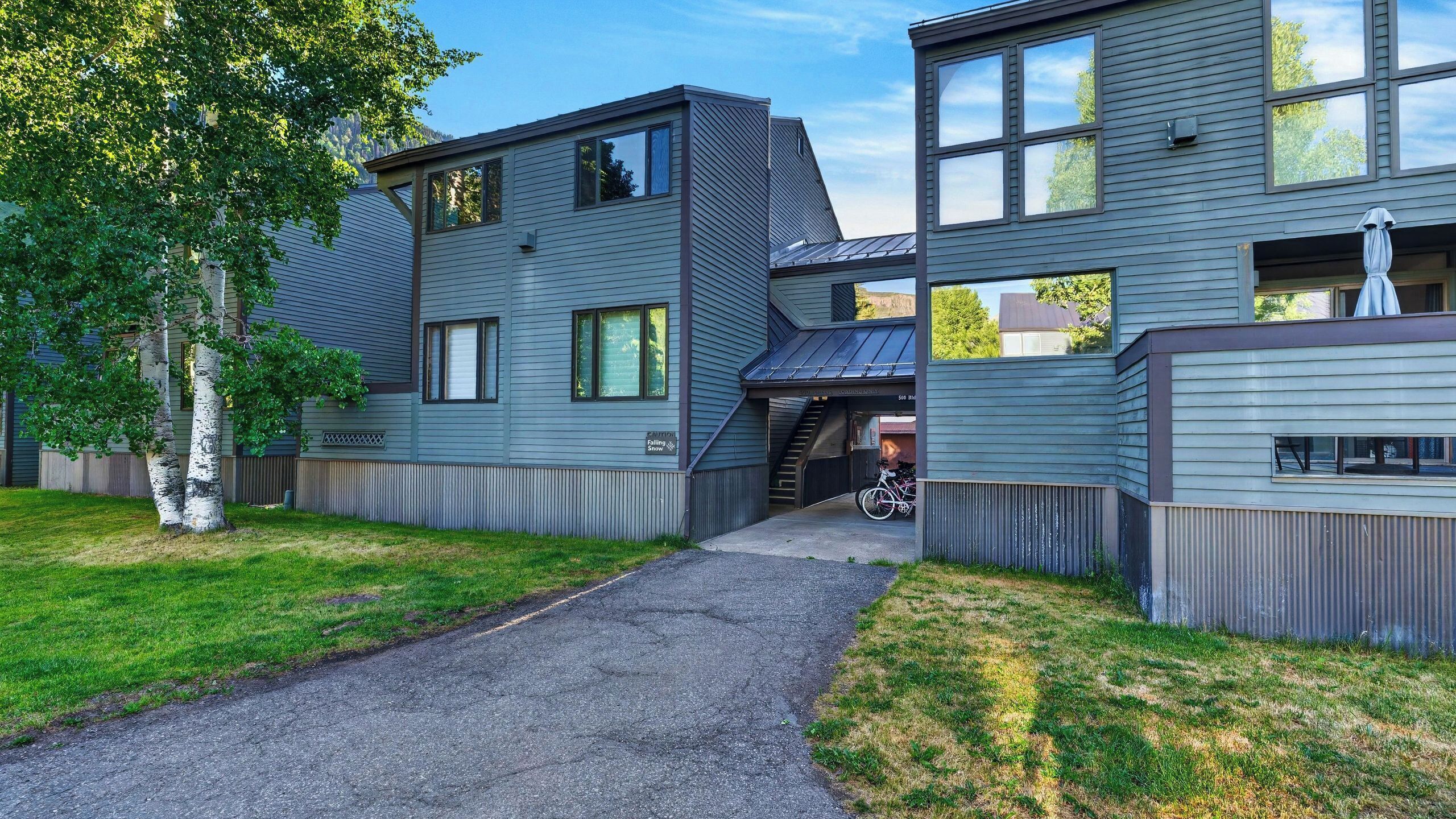 Une maison moderne à deux étages, dotée d’un porche et d’un escalier apparent menant à l’étage supérieur.
