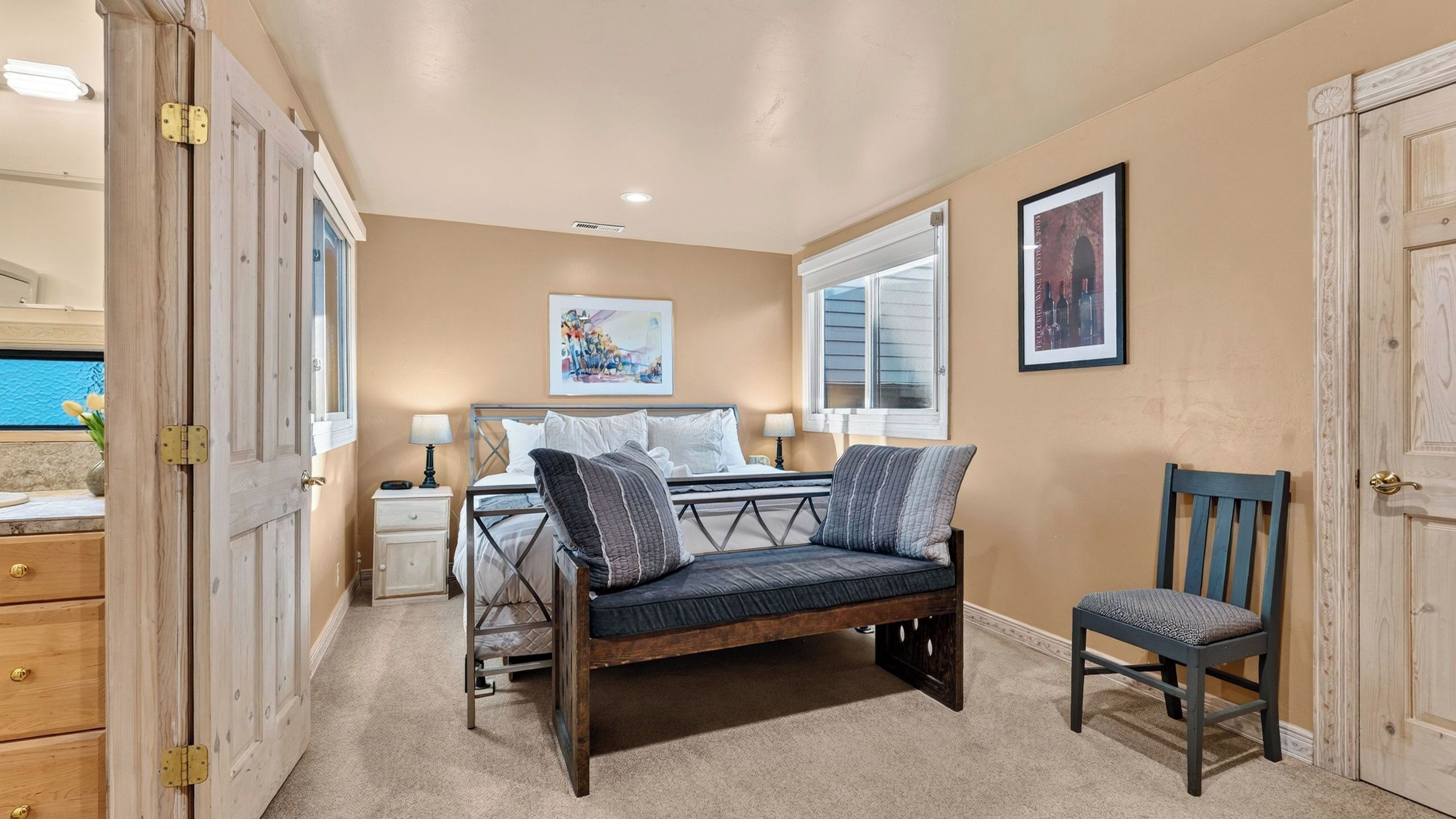 A bedroom with a bed, bedside tables, a chair, and artwork on the walls.