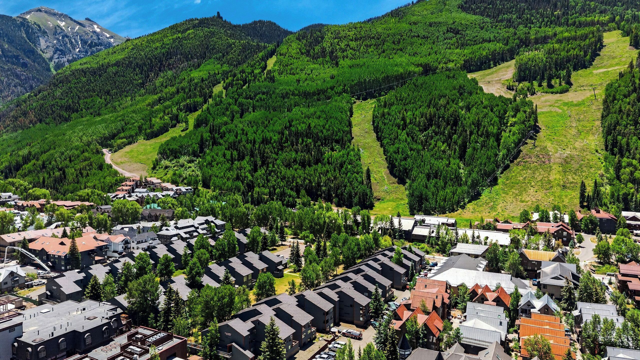 A mountainous area with a residential community featuring modern buildings, roads, and dense forested hills.