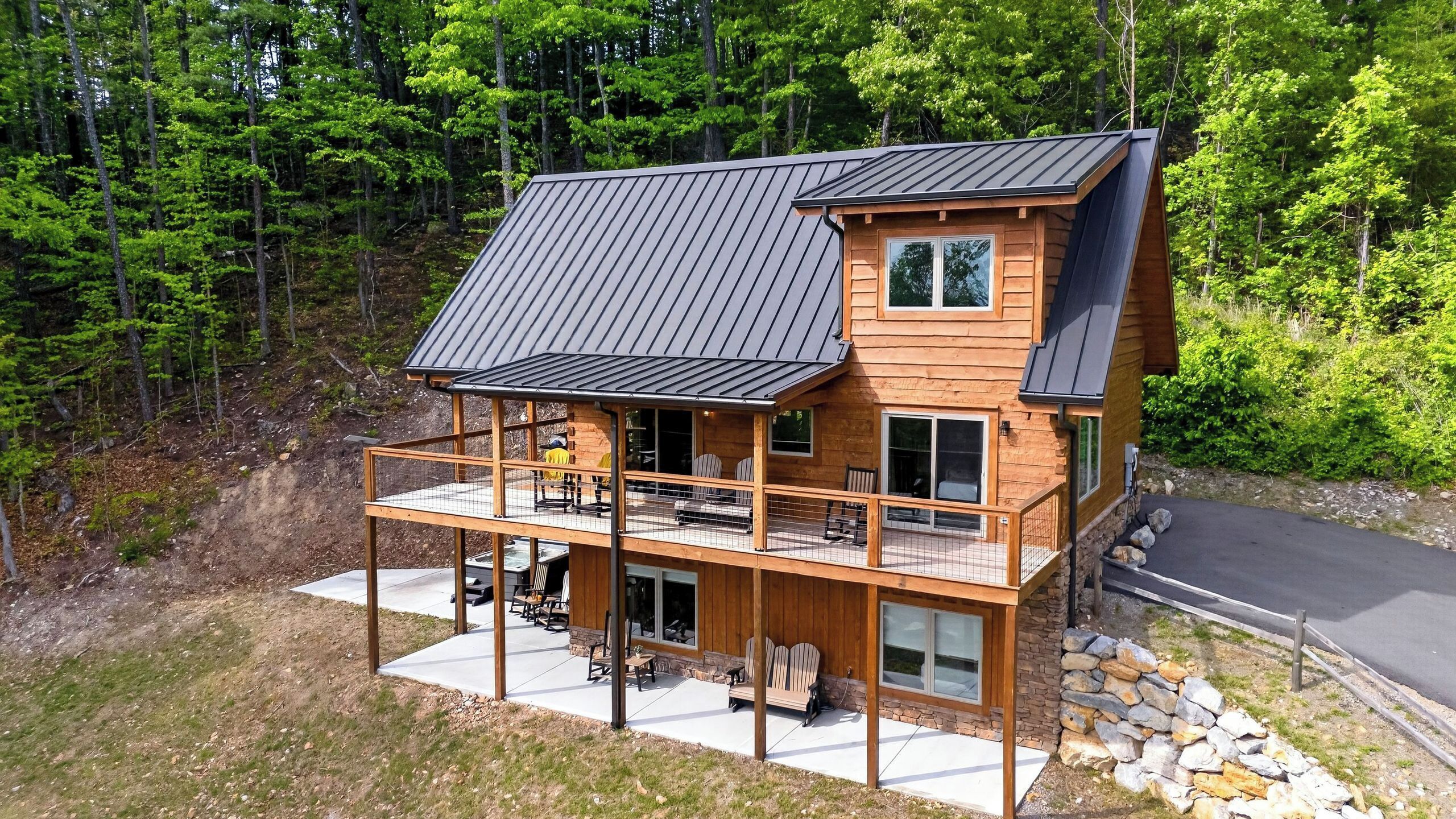 A two-story log cabin with a balcony, a deck, and a stone wall.