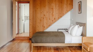 Ein Schlafzimmer mit Holzbalkendecke, einem Bett mit weißer Bettwäsche und Holzboden.