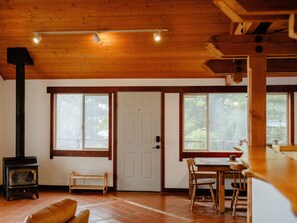 A wooden interior with a fireplace, a dining area, and large windows. - Blue whale cove | Cliffside Ocean Views | Hot tub (Whitethorn)