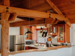 Een keuken met houten balken, roestvrijstalen apparatuur en hangende potten.