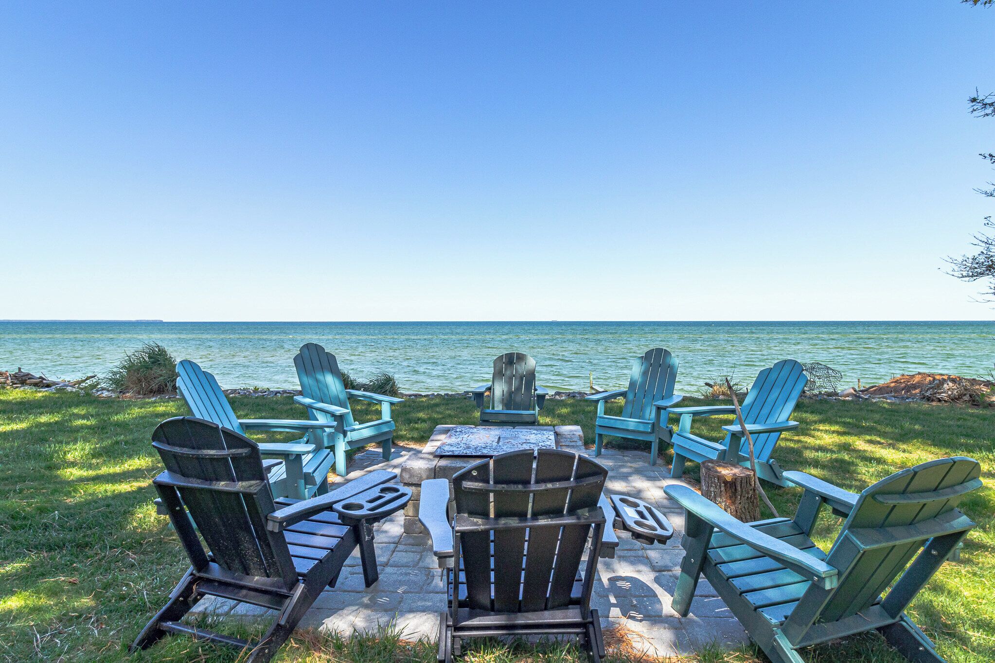 A lakeside seating area with Adirondack chairs and a fire pit.