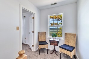 Ein Eckzimmer mit Fenster, Tür und zwei Korbstühle mit dunklen Kissen.