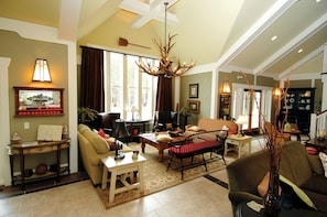 A spacious living room with a chandelier, a fireplace, and a dining area.