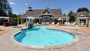 A pool with a 'SHALLOW AREA NO DIVING' sign, lounge chairs, and a building with a stone facade.