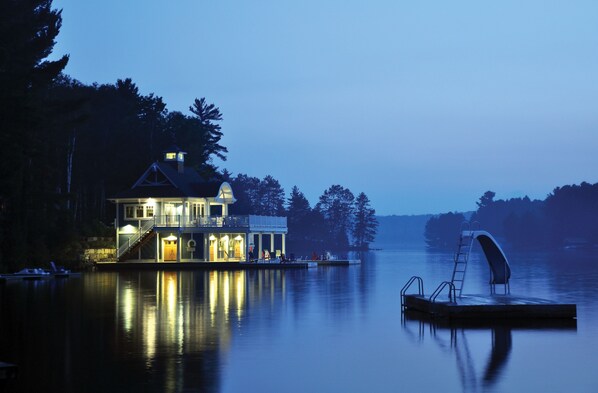 A waterfront house with a dock, a staircase, and a pool area.