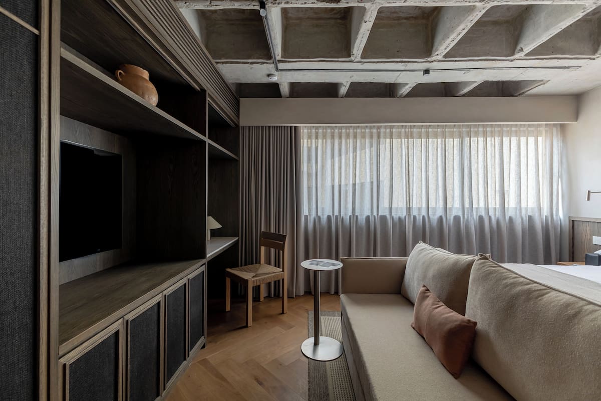 Une chambre d’hôtel moderne équipée d’un canapé, d’une télévision, d’une petite table et d’une chaise.