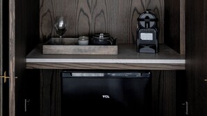Une petite cuisine équipée d’une machine à café, d’une bouilloire, d’un verre à vin et d’un petit placard.