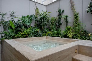 Un jacuzzi rodeado de exuberante vegetación en un ambiente interior moderno.