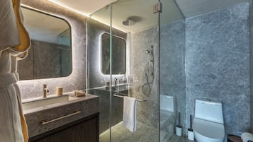 Un baño moderno con ducha de vidrio, lavamanos de mármol y retrete.