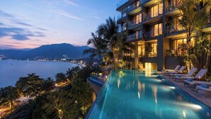 A hotel with a pool, balconies, and a view of the sea.