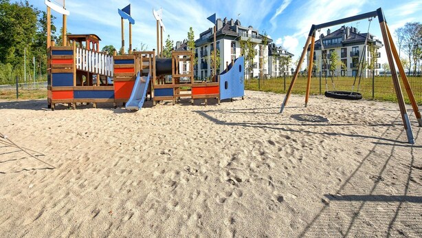 A playground with various play structures, including slides and climbing areas, surrounded by a sandy area. - Premium Dziwnow Coastal Apartment for 3 (Dziwnów)