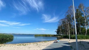 A clear sky, a calm lake, a sandy beach, and a wooden boardwalk. - Premium Dziwnow Coastal Apartment for 3 (Dziwnów)