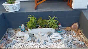 A garden with a wooden table, potted plants, and decorative rocks.