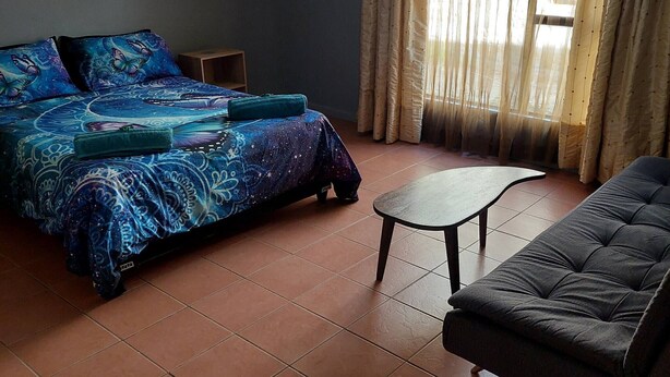 A room with a bed, a sofa, a small table, and a window with curtains.