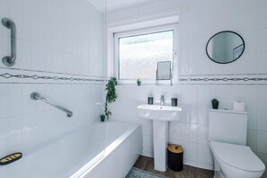 A modern bathroom with a bathtub, sink, toilet, and a window with a mirror. - Huge 4BR House | Driveway | Pool Table (Birkby)