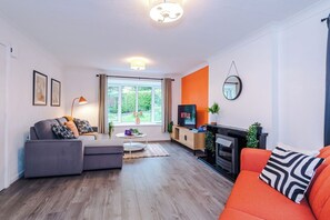 Een moderne woonkamer met een bank, een salontafel, een televisie en een open haard.