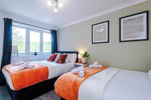 A hotel room with two beds, a window with curtains, a ceiling light, and two framed pictures on the wall. - Huge 4BR House | Driveway | Pool Table (Birkby)