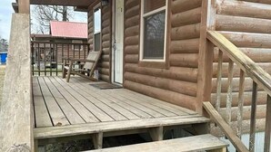 A wooden cabin with a porch, a door, and a window. - Cozy Cabin #2 Near Lake Merrisach in Tichnor AR (Tichnor)