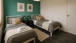 Een slaapkamer met twee bedden, een witte deur en kunst aan de muur.