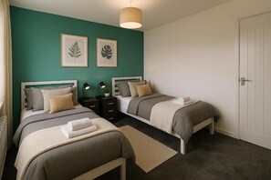Une chambre avec deux lits, une porte blanche et des œuvres d’art accrochées au mur.