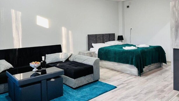 A modern bedroom with a bed, a sofa, a coffee table, and a small side table.