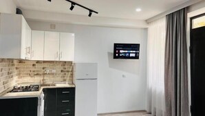 A modern kitchen with a built-in stove, a refrigerator, and a wall-mounted TV.