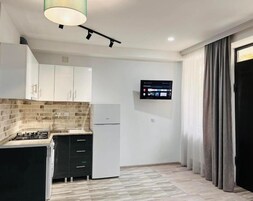 Una cocina moderna con estufa integrada, refrigerador y televisor montado en la pared.