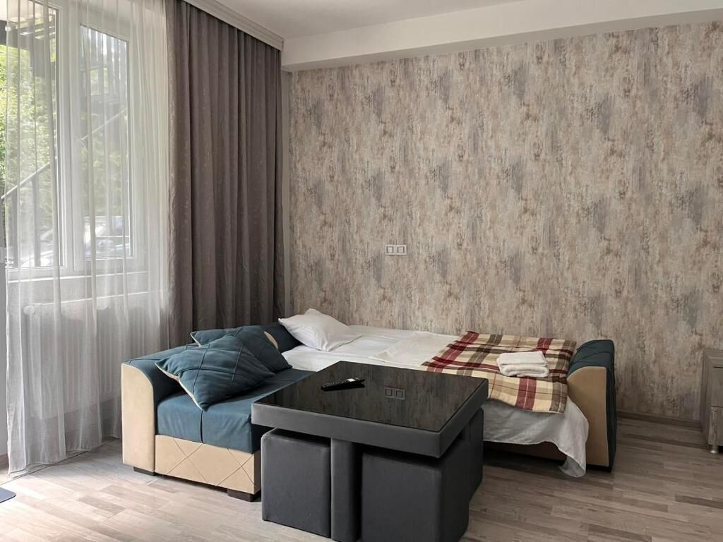 A modern living room with a sofa, a coffee table, and a bed.