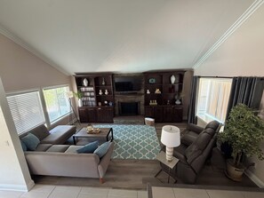 Ein Wohnzimmer mit einer Couch, einem Couchtisch, einem Fernseher und einem Kamin.