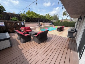 Eine Holzterrasse mit Gartenmöbeln, einem Pool und Lichterketten.