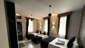 A hotel room with two single beds, a desk, a chair, a wardrobe, and a ceiling light fixture. - bütünoğlu pansiyon (Antalya)